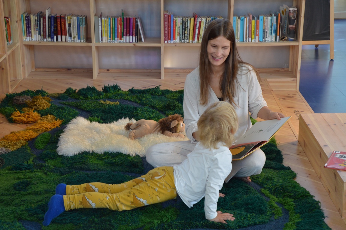 Rebekka Kvelland leser høyt for gutt som gjør en yogaøvelse
