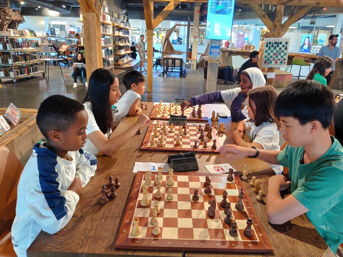 Barn i gruppe på to og to som sitter på rekke og rad, dypt konsentrert i sjakkspill