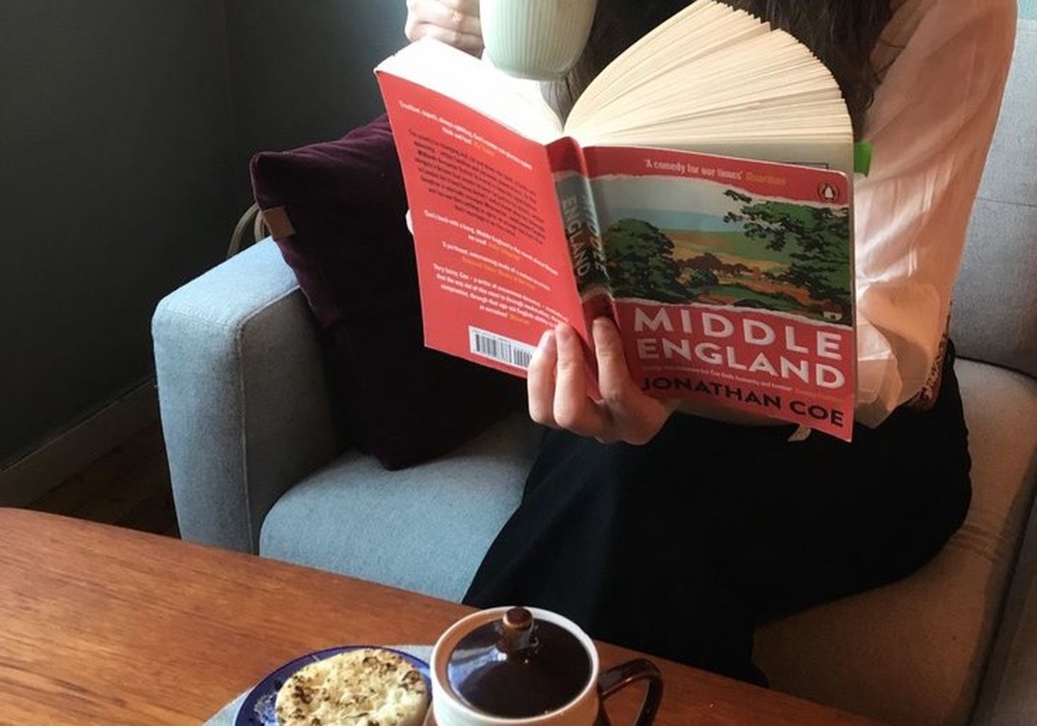 Kvinne drikker kaffe og leser bok.