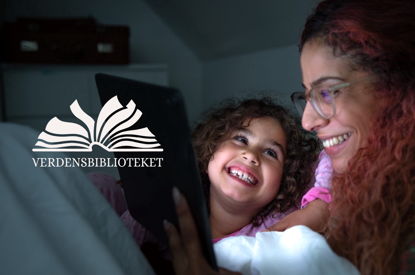Mor og datter smiler til hverandre mens de leser på nettbrett